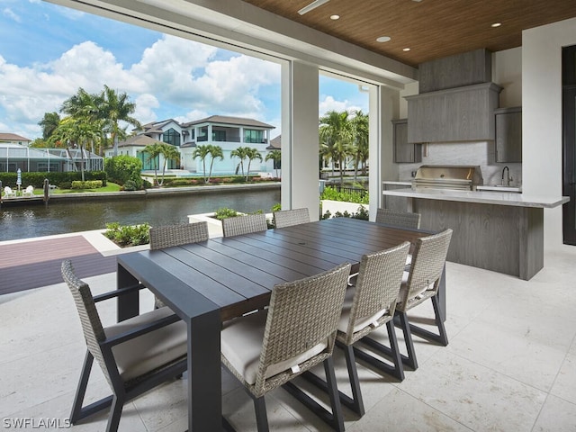 view of patio / terrace with area for grilling, a wet bar, and a water view