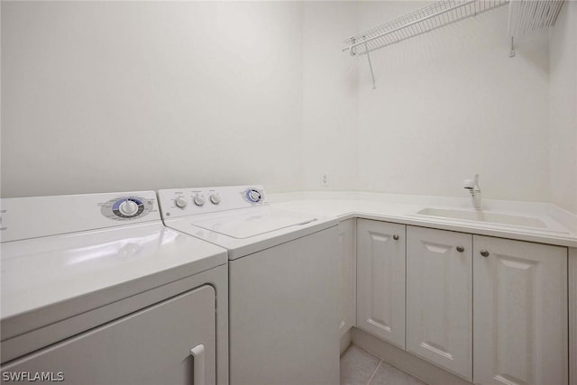 laundry room with washing machine and dryer, sink, light tile patterned floors, and cabinets