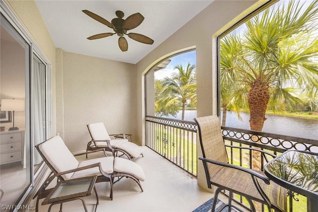 sunroom with ceiling fan, a water view, and lofted ceiling