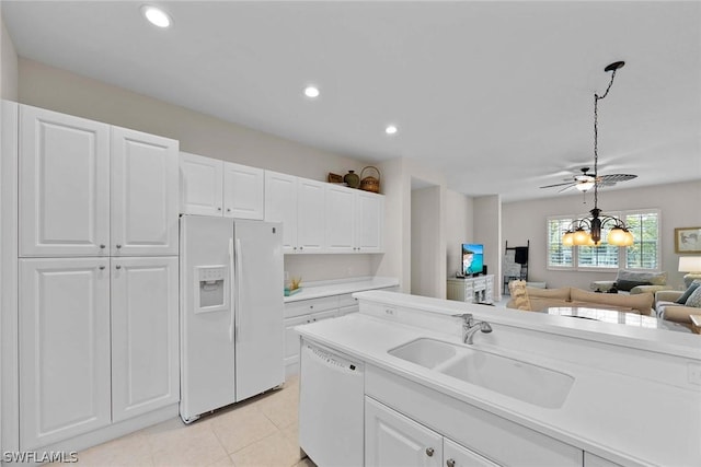 kitchen with white appliances, ceiling fan with notable chandelier, sink, light tile patterned floors, and white cabinetry