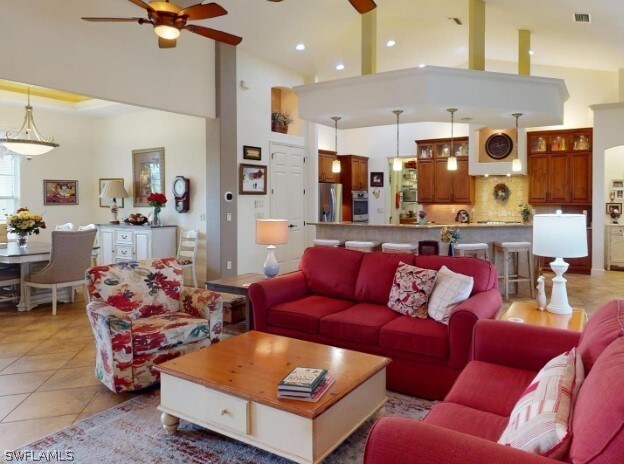 living room featuring a towering ceiling, ceiling fan, and light tile floors