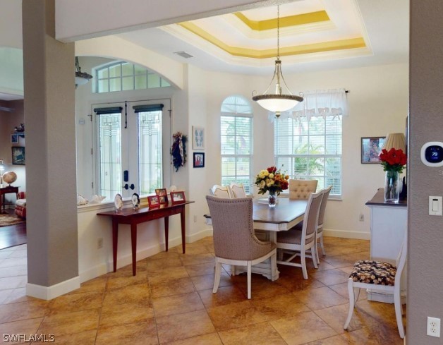 tiled dining space with a raised ceiling and french doors