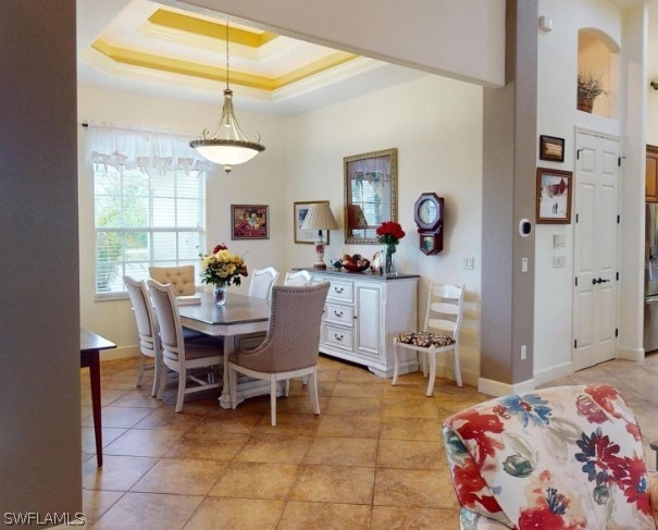 dining room featuring a tray ceiling and light tile floors