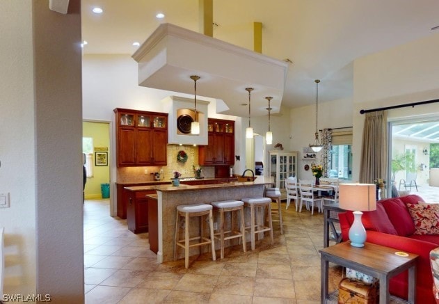 kitchen featuring a center island, hanging light fixtures, tasteful backsplash, and light tile flooring