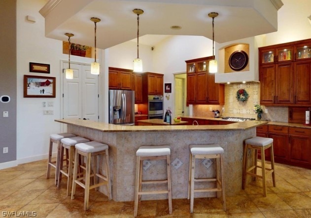 kitchen featuring appliances with stainless steel finishes, tasteful backsplash, light tile floors, and pendant lighting