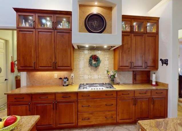 kitchen featuring backsplash, light stone counters, light tile floors, and stainless steel gas stovetop