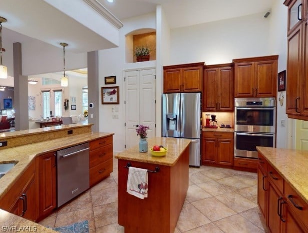 kitchen with stainless steel appliances, hanging light fixtures, a center island, and light tile floors