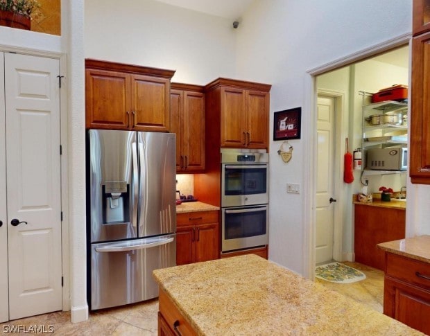 kitchen featuring light stone countertops, light tile floors, and stainless steel appliances