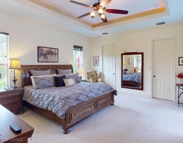 bedroom with ceiling fan, multiple windows, a tray ceiling, and carpet