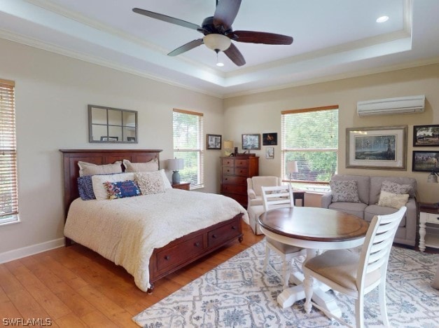 bedroom featuring ceiling fan, a tray ceiling, crown molding, a wall mounted air conditioner, and wood-type flooring