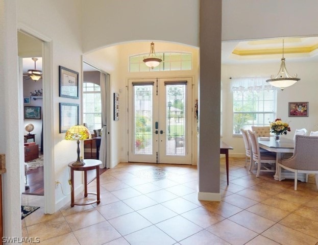 entryway featuring a raised ceiling, tile floors, ceiling fan, and french doors