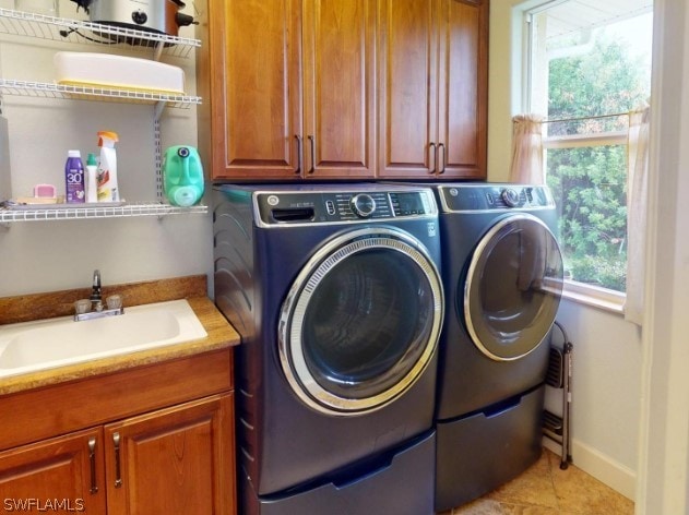 washroom featuring sink, washing machine and clothes dryer, cabinets, and light tile floors