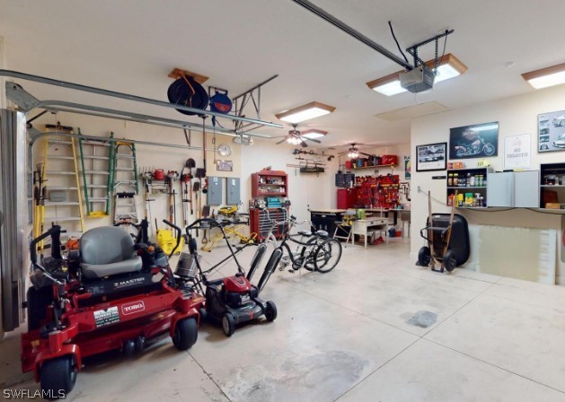 garage with a workshop area, a garage door opener, and ceiling fan