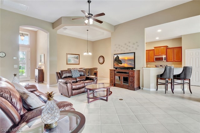 tiled living room with ceiling fan with notable chandelier