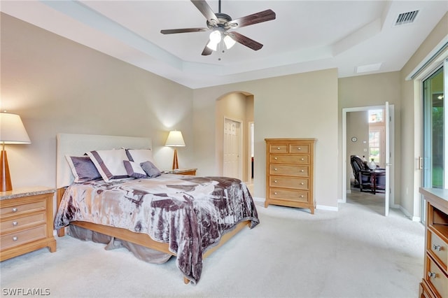 bedroom with ceiling fan, a raised ceiling, and light carpet