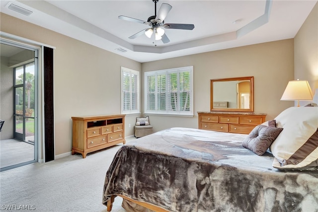 bedroom featuring ceiling fan, a raised ceiling, access to outside, and multiple windows