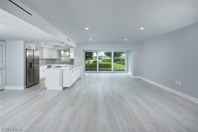 kitchen featuring white cabinets, light hardwood / wood-style floors, pendant lighting, and stainless steel fridge