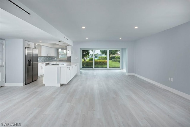 kitchen featuring stainless steel fridge with ice dispenser, open floor plan, light countertops, decorative backsplash, and white cabinetry