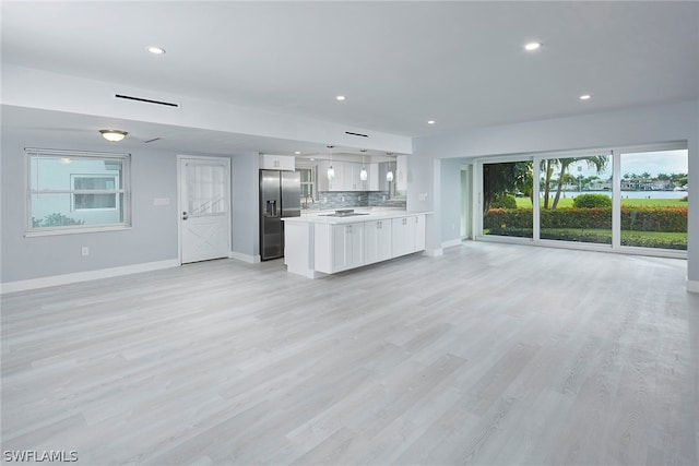 kitchen featuring a wealth of natural light, stainless steel fridge, pendant lighting, and light hardwood / wood-style floors