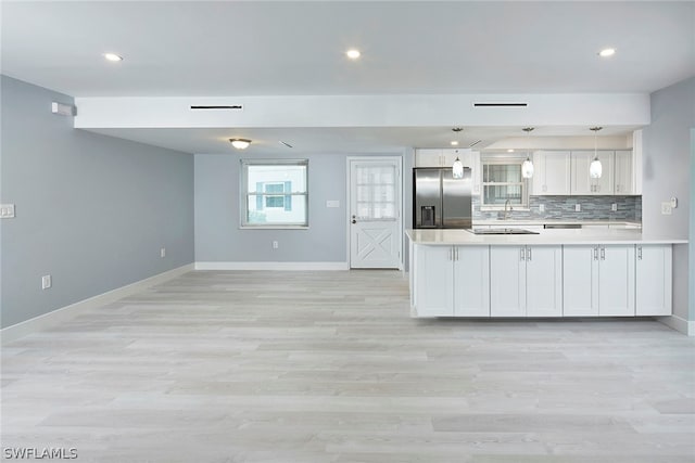 kitchen with light hardwood / wood-style floors, white cabinetry, hanging light fixtures, and stainless steel fridge with ice dispenser