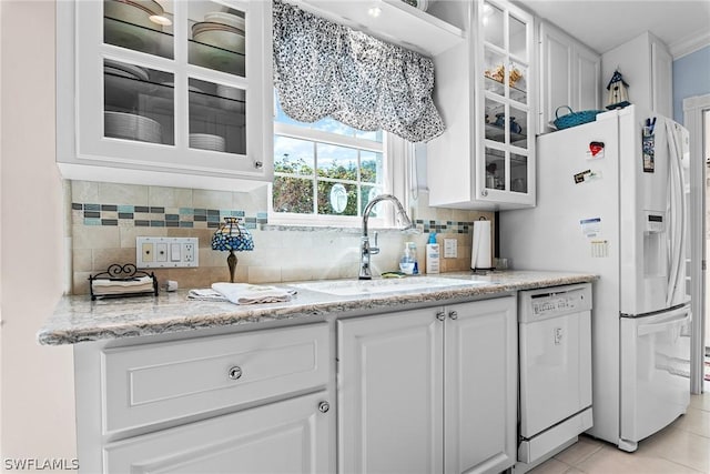 kitchen featuring white appliances, light stone countertops, sink, white cabinets, and backsplash