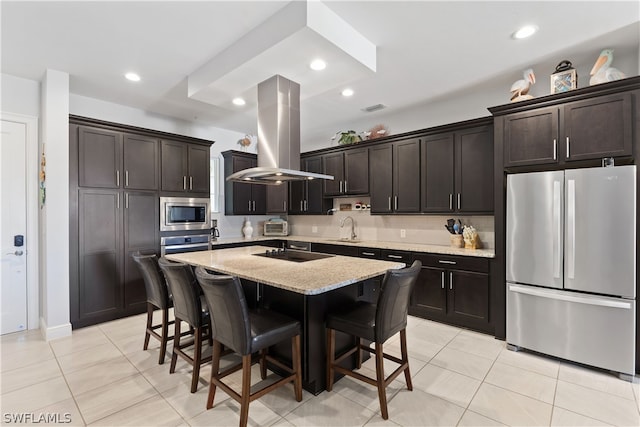 kitchen with dark brown cabinets, stainless steel appliances, island range hood, sink, and a kitchen island