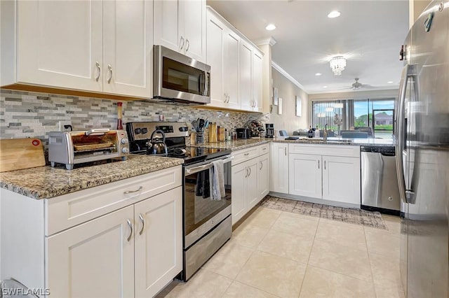 kitchen featuring ceiling fan, white cabinetry, stainless steel appliances, and ornamental molding