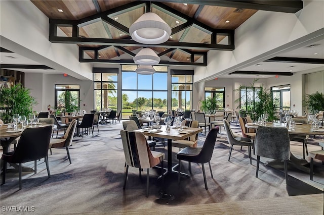 carpeted dining space with beam ceiling, high vaulted ceiling, plenty of natural light, and wood ceiling