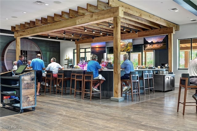 bar featuring beamed ceiling, rail lighting, and hardwood / wood-style flooring