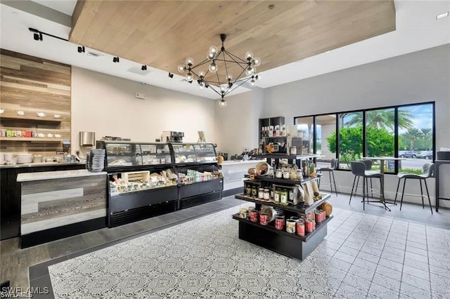 playroom featuring wood walls, wood ceiling, a towering ceiling, and an inviting chandelier