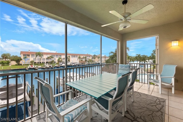 sunroom / solarium featuring ceiling fan and a water view