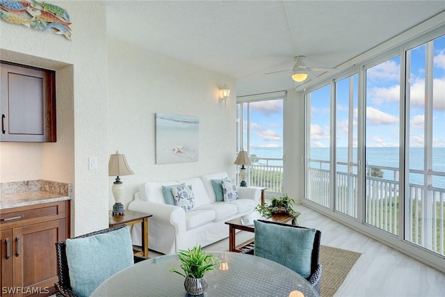 sunroom / solarium featuring a water view and ceiling fan