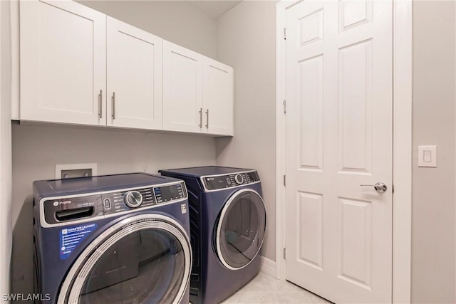 washroom featuring cabinets, light tile patterned floors, and washer and clothes dryer