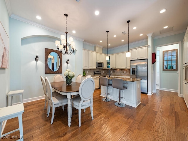 dining space featuring sink, an inviting chandelier, ornamental molding, and light wood-type flooring