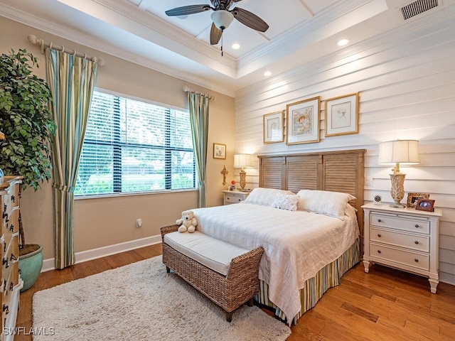 bedroom with light wood-type flooring, a tray ceiling, ceiling fan, and ornamental molding