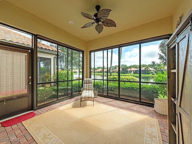 unfurnished sunroom featuring a water view and ceiling fan