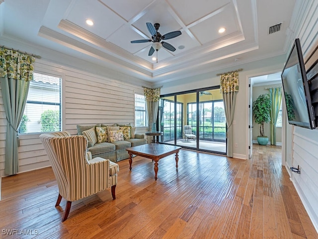 living room featuring ceiling fan, light hardwood / wood-style floors, coffered ceiling, and ornamental molding