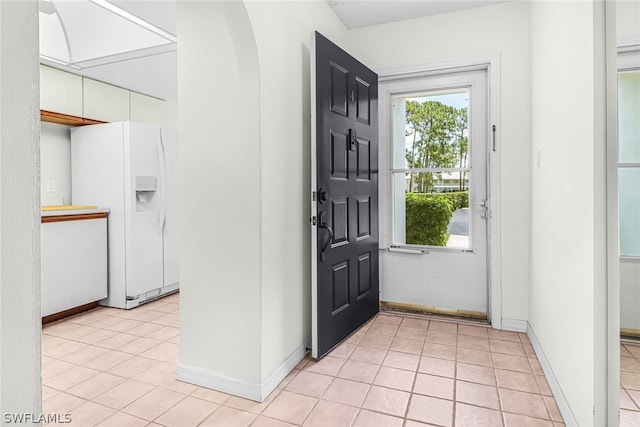 entrance foyer with light tile patterned floors, baseboards, and arched walkways