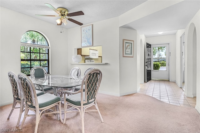 dining space with a textured ceiling, ceiling fan, and light carpet