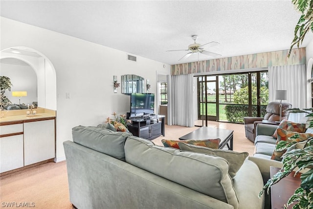 carpeted living room with ceiling fan, sink, and a textured ceiling