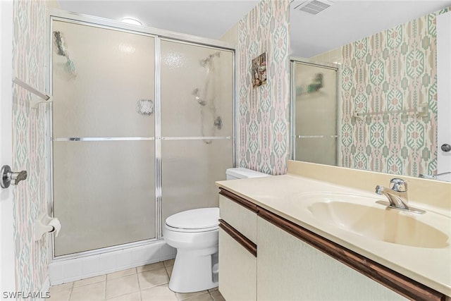 bathroom with tile patterned floors, vanity, a shower with shower door, and toilet