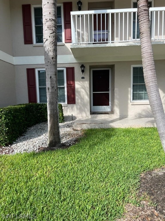 doorway to property with a balcony and a yard