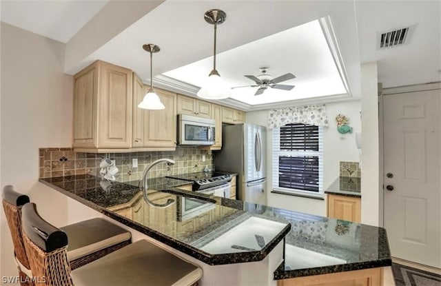 kitchen featuring ceiling fan, a raised ceiling, kitchen peninsula, and appliances with stainless steel finishes