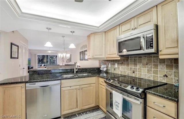 kitchen featuring hanging light fixtures, dark stone countertops, stainless steel appliances, kitchen peninsula, and sink