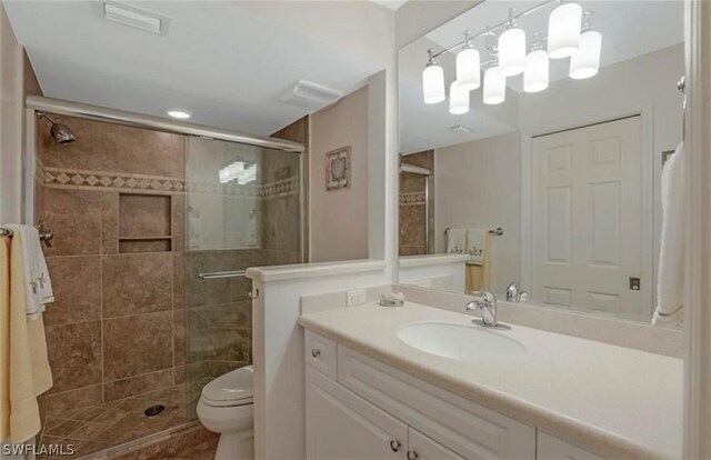 bathroom featuring a shower with door, toilet, and vanity