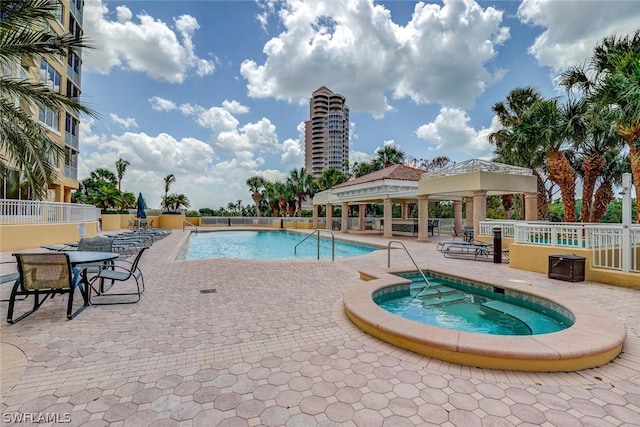 pool with a community hot tub, fence, a gazebo, and a patio