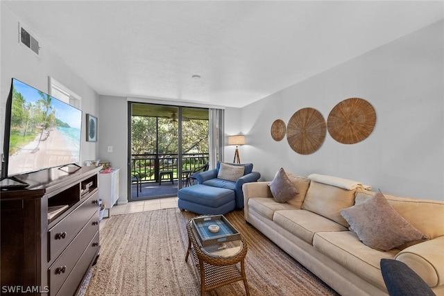 living area with a wall of windows, visible vents, and light tile patterned flooring