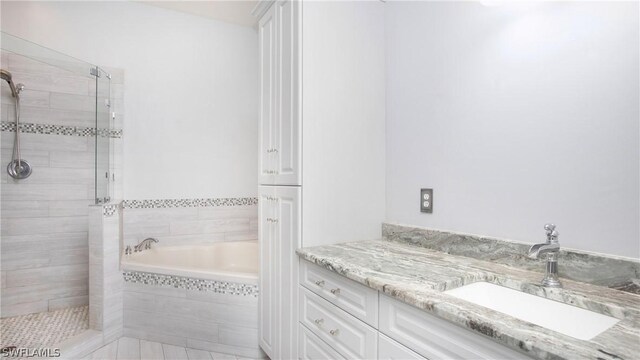 bathroom with tile patterned floors, vanity, and shower with separate bathtub