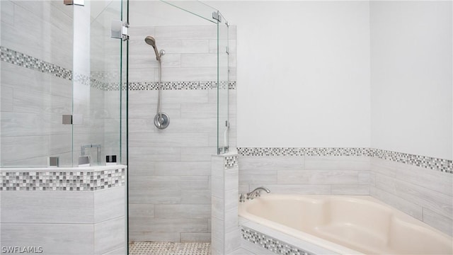 bathroom featuring a shower stall and a bath