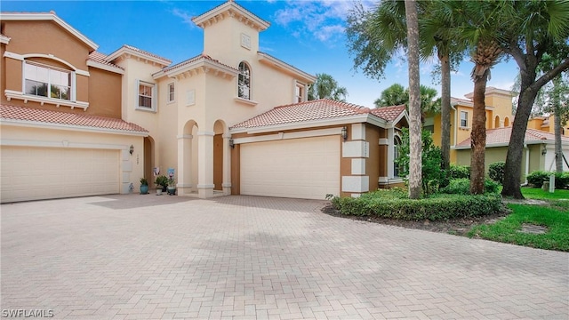 mediterranean / spanish home with a tiled roof, decorative driveway, and stucco siding